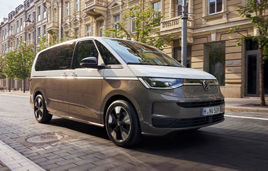 Silberner Volkswagen Multivan steht auf gepflasterter Straße vor mehrstöckigen Altbauten